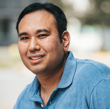 A picture of a man with light brown skin, black short hair, and a blue shirt